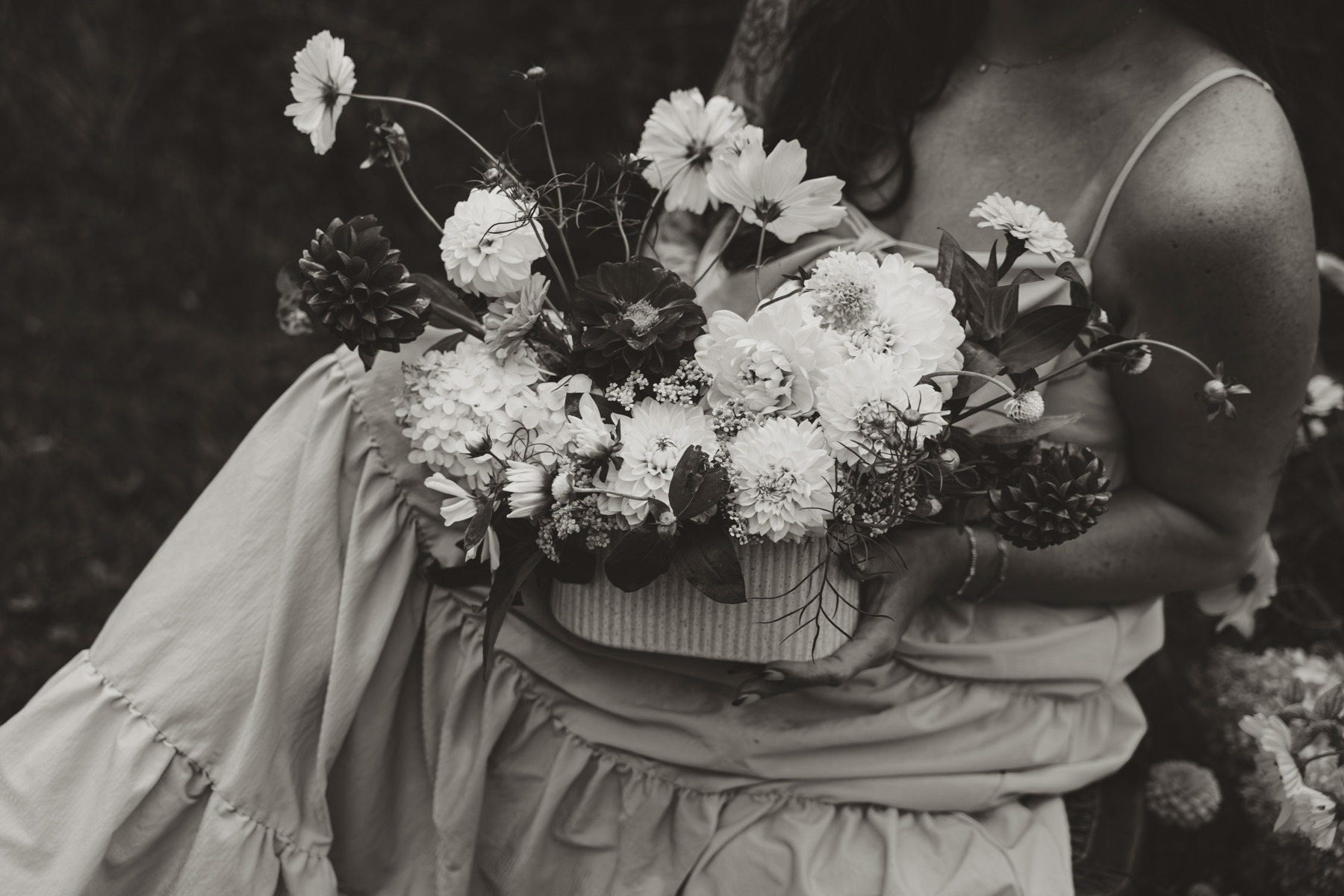 Black-and-white portrait of a woman holding an arrangement of garden flowers